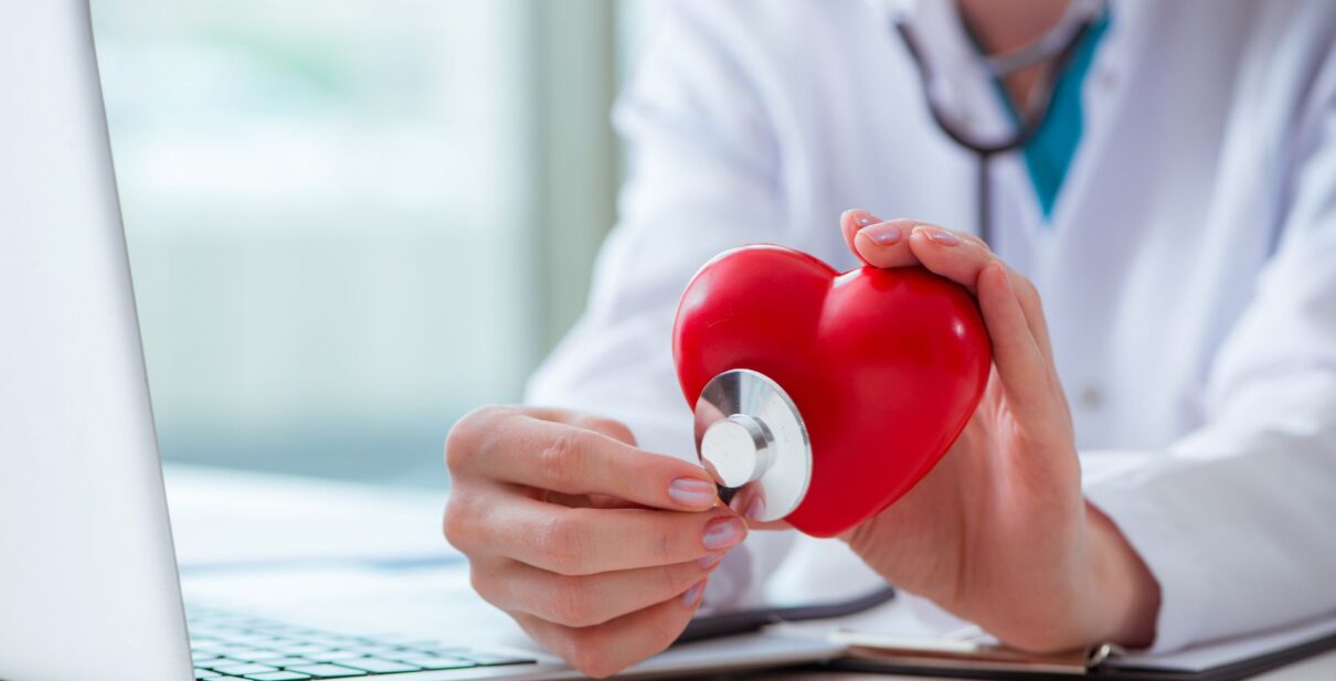 Cardiologist reviewing a patient’s heart screening results with a stethoscope and ECG monitor, symbolizing early detection and preventive heart care.