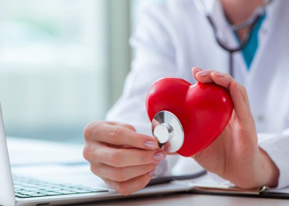 Cardiologist reviewing a patient’s heart screening results with a stethoscope and ECG monitor, symbolizing early detection and preventive heart care.