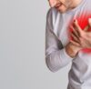 Person holding chest showing early sign of heart disease